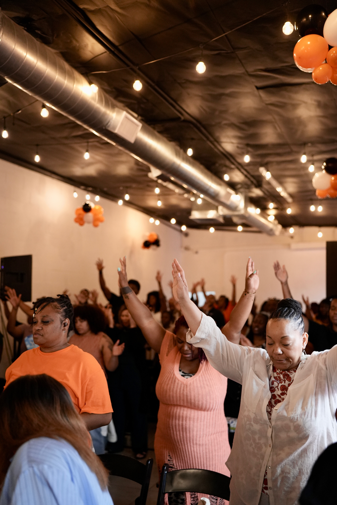 C4 congregation worshiping with hands raised during a Sunday gathering